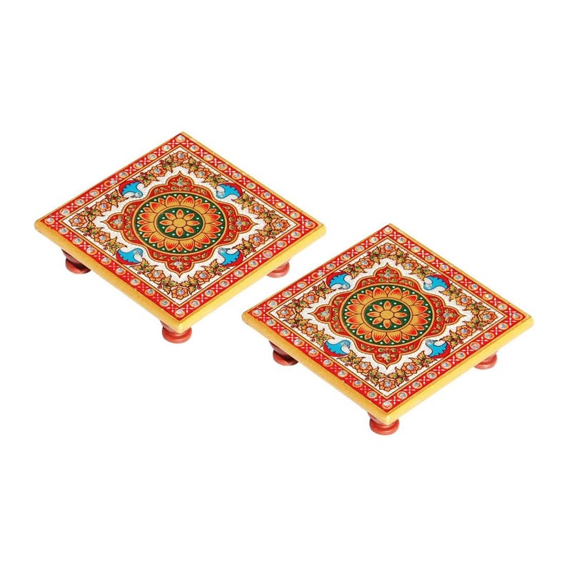 May include: Two square wooden stands featuring a vibrant hand-painted floral mandala design in shades of red, green, yellow, and blue. Each stand is supported by four small, rounded feet and displays intricate, symmetrical patterns on the top surface.