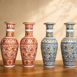 Könnte beinhalten: Vier dekorative Keramikvasen mit aufwendigen Blumenmustern. Zwei Vasen weisen rot-weiße Designs auf, während die anderen beiden blaue und weiße Muster zeigen. Die Vasen stehen auf einer Holzoberfläche.