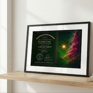 Può includere: Certificato incorniciato di proprietà di una stella con il testo "A Unique Star" e "A Special Tribute". Il certificato ha un bordo verde scuro e un'immagine di nebulosa colorata. La cornice è nera e poggia su una mensola di legno.