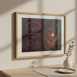 Può includere: Certificato incorniciato di proprietà di una stella con il testo "A Unique Star" e "A Special Tribute". Il certificato presenta un'immagine di nebulosa con sfumature arancioni e blu. La cornice è marrone chiaro e si trova su una superficie di legno.