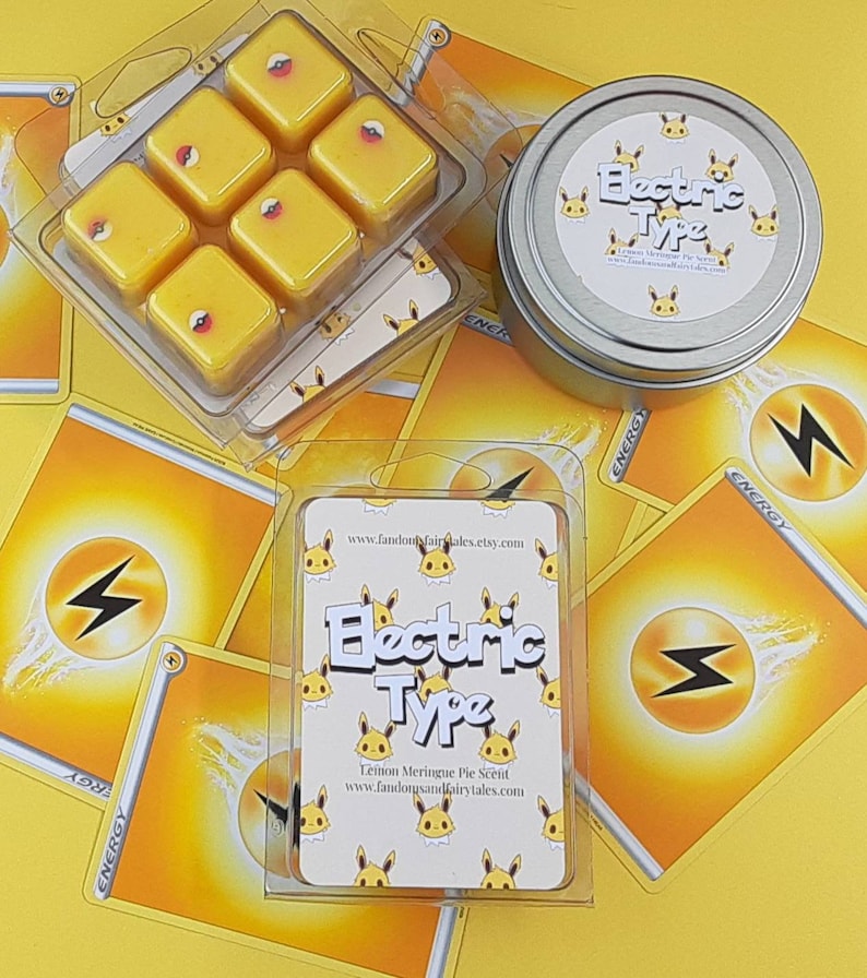 May include: A set of six yellow wax melts in a clear plastic container. The wax melts are shaped like squares and have a small red circle in the center of each square. The container is surrounded by yellow and white playing cards with the word "ENERGY" printed on them. The container also has a label that says "Electric Type" and "Lemon Meringue Pie Scent".