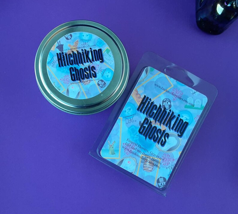 Puede incluir: Un recipiente de pl&aacute;stico transparente con un dise&ntilde;o azul y dorado. El recipiente tiene el texto "Hitchhiking Ghosts" y "Funeral Flowers, Graveyard Dirt and 090 Happy Haunts" impreso en &eacute;l. El recipiente est&aacute; sentado sobre una superficie morada.