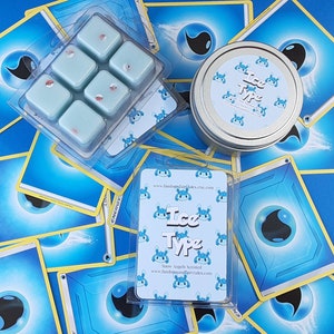 May include: A set of six small, square, blue wax melts with a white background. The wax melts are arranged in a grid pattern. The wax melts are labeled "Ice Type" and are snow angel scented. The wax melts are packaged in a clear plastic box with a white background. The box is labeled with the website address "www.fandomsoffairytales.etsy.com".