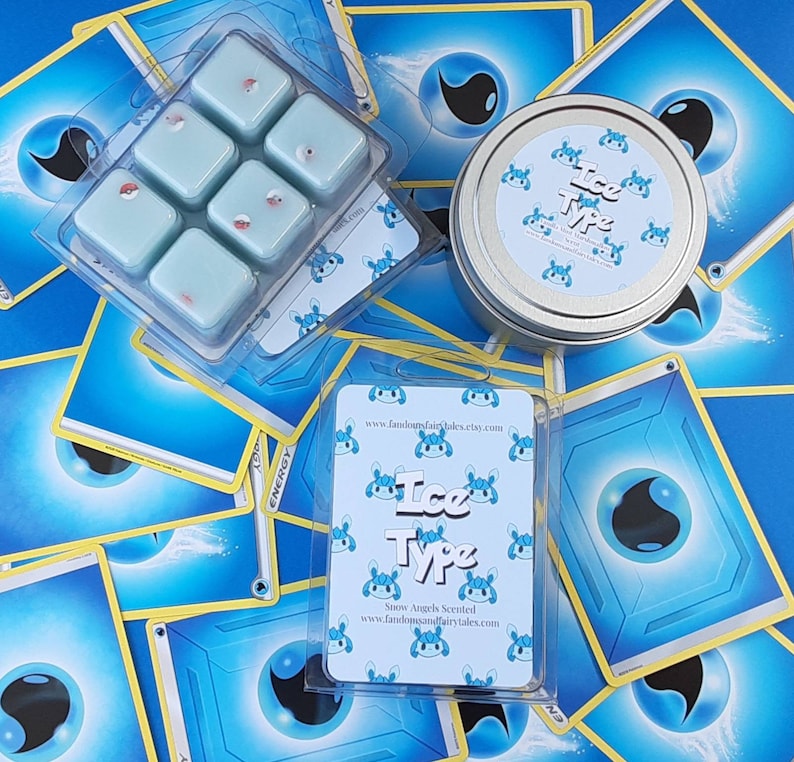 May include: A set of six small, square, blue wax melts with a white background. The wax melts are arranged in a grid pattern. The wax melts are labeled "Ice Type" and are snow angel scented. The wax melts are packaged in a clear plastic box with a white background. The box is labeled with the website address "www.fandomsoffairytales.etsy.com".