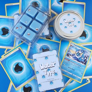 May include: A set of six blue wax melts in a clear plastic container. The container is surrounded by Pokemon trading cards featuring water-type Pokemon. The wax melts are scented with a seaside scent and are labeled "Water Type".