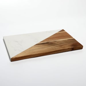 Può includere: Vassoio rettangolare con un design diviso in diagonale. Una metà è in marmo bianco, l'altra in legno naturale. Il lato in legno ha venature visibili e un colore marrone caldo. Ideale per servire antipasti o salumi.
