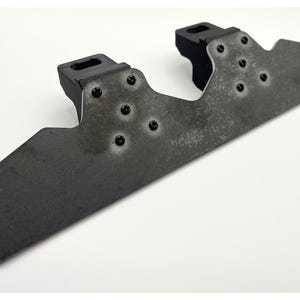 May include: A dark grey metal bracket featuring two black rubber mounts and several black screws. The bracket has a distressed finish and an unusual shape, possibly for mounting or support.
