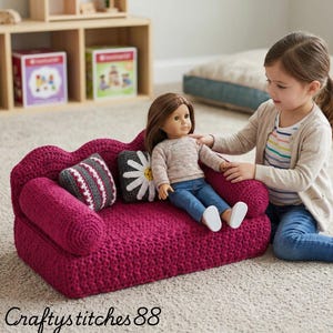 May include: A handcrafted, magenta-colored crochet doll sofa with two matching pillows. One pillow has a daisy design, and the other has a striped pattern. A doll is seated on the sofa. The text "Craftystitches88" is at the bottom.