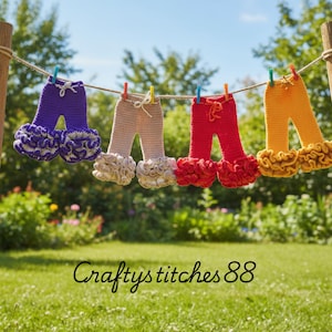 May include: Four pairs of colourful, crocheted baby trousers with ruffled bottoms hang on a washing line. The trousers are purple, beige, red, and yellow, each secured with a clothes peg. The text "Craftystitches88" is at the bottom.