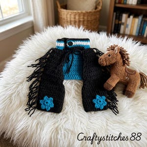 Peut inclure: Une paire de jambi&egrave;res en crochet noir avec de longues franges noires, des fleurs bleu vif et une ceinture ray&eacute;e bleu et blanc dot&eacute;e d'un bouton noir, accompagn&eacute;e d'une petite peluche de cheval de couleur marron.
