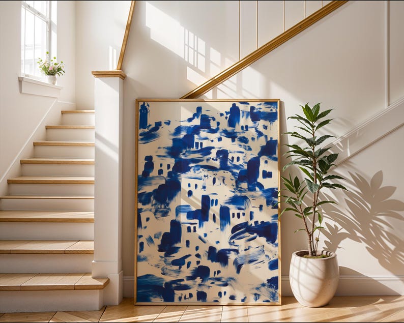 a large blue and white abstract painting displayed on a wall, with a potted plant and a staircase visible in the background.