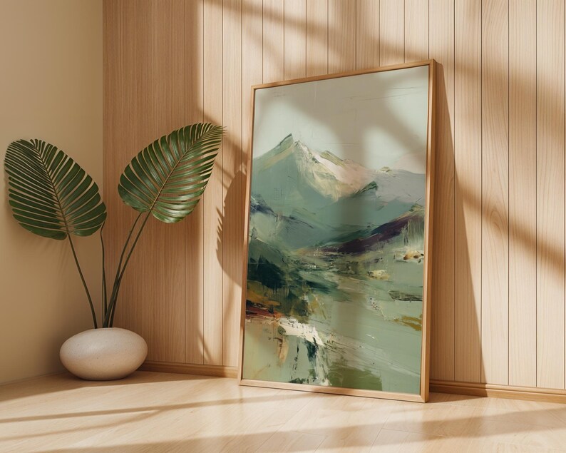 a large framed painting of a mountain landscape, placed on a wooden wall next to a potted plant.