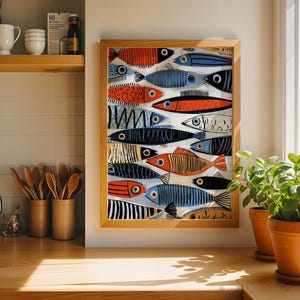 a kitchen counter with a framed fish painting hanging on the wall above it. The painting depicts a group of colorful fish swimming together. The kitchen counter also has various kitchen utensils, such as spoons, arranged in small containers. There are two potted plants on the counter, one on the left and one on the right, adding a touch of greenery to the space.