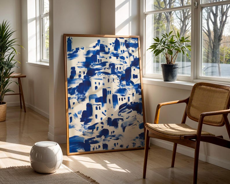 a large blue and white abstract painting displayed on a wall, with a wooden chair and a potted plant nearby.
