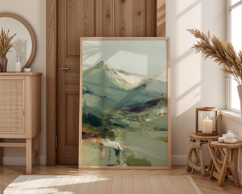 a large, abstract painting of a mountainous landscape, displayed in a wooden frame and placed in a room with a mirror, a wooden cabinet, and some decorative elements.