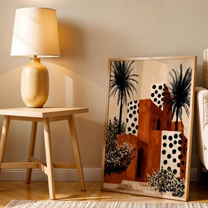 a living room with a wooden side table, a lamp, and a framed artwork depicting a tropical scene with palm trees and a building with a distinctive orange and white color scheme.