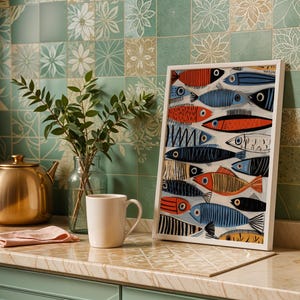 a kitchen counter with a framed fish-themed artwork, a teapot, a white mug, a vase with greenery, and a gold bowl.