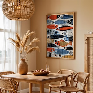 a cozy dining area with a wooden table, chairs, and a woven basket. A large fish-themed painting is hanging on the wall above the table, and a woven basket is placed on the table. The room has a warm, inviting atmosphere with natural light coming in through a window.