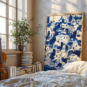 a cozy bedroom scene with a large blue and white abstract painting on the wall, a wooden bed with white sheets, a stack of books, and a potted plant.