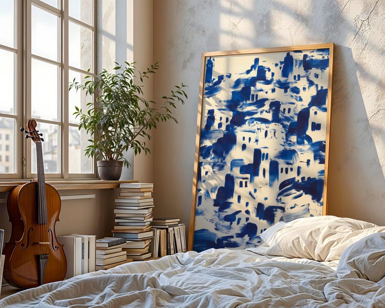 a cozy bedroom scene with a large blue and white abstract painting on the wall, a wooden bed with white sheets, a stack of books, and a potted plant.