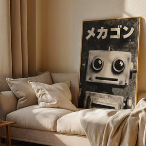 a large black and white poster of a robot on a wall, with a beige couch and a wooden side table in the foreground.