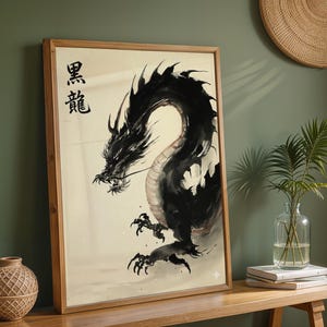 a framed artwork of a black dragon with a Chinese character above it, placed on a wooden shelf next to a vase with a plant and some books.