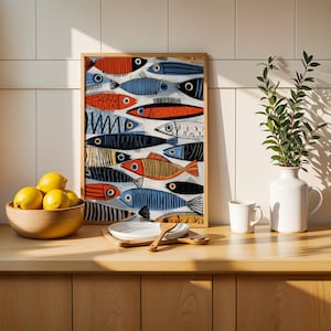 a kitchen counter with a framed fish painting, a bowl of lemons, a white vase with a plant, and a set of wooden utensils.