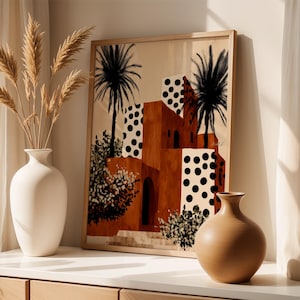 a framed painting of a desert-like scene with palm trees and buildings, placed on a shelf next to two white vases.