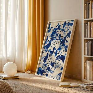 a cozy living room with a large framed painting of a blue and white abstract design hanging on the wall, a bookshelf filled with books, and a white sphere on the floor.
