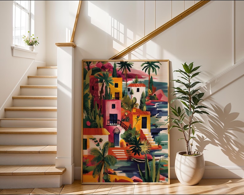 a colorful painting of a tropical village, with buildings, palm trees, and a body of water, displayed on a wall in a bright and sunny room with a staircase and potted plants.