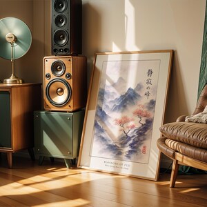 a living room with a large framed poster of a serene landscape, a brown leather chair, a wooden side table with a lamp, and a stack of speakers.