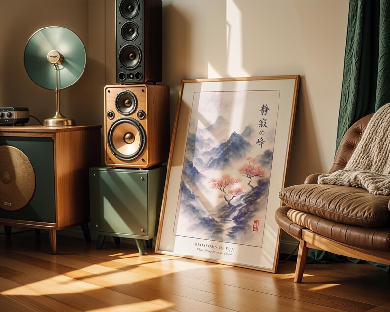 a living room with a large framed poster of a serene landscape, a brown leather chair, a wooden side table with a lamp, and a stack of speakers.