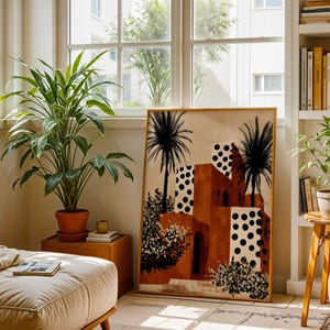 a cozy living room with a large window, a potted plant, a wooden side table, and a large painting of a tropical building with palm trees.