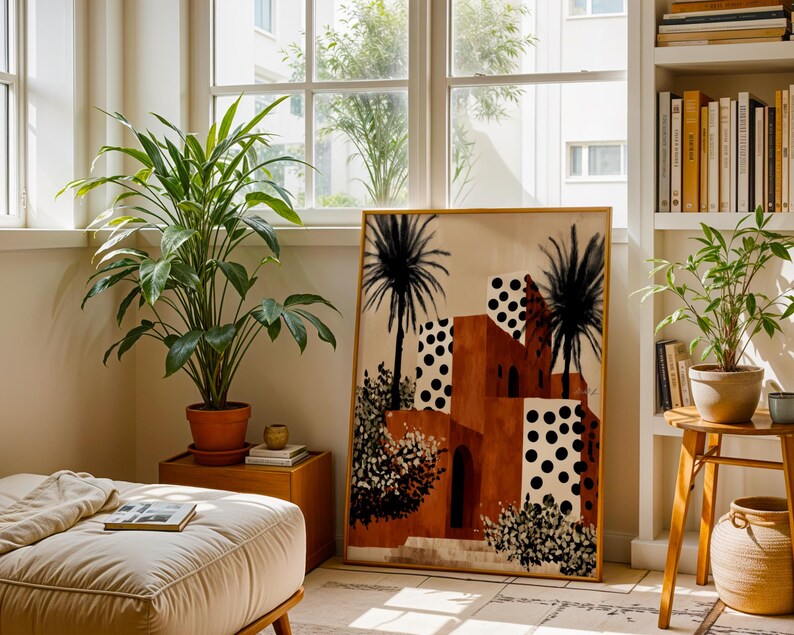 a cozy living room with a large window, a potted plant, a wooden side table, and a large painting of a tropical building with palm trees.