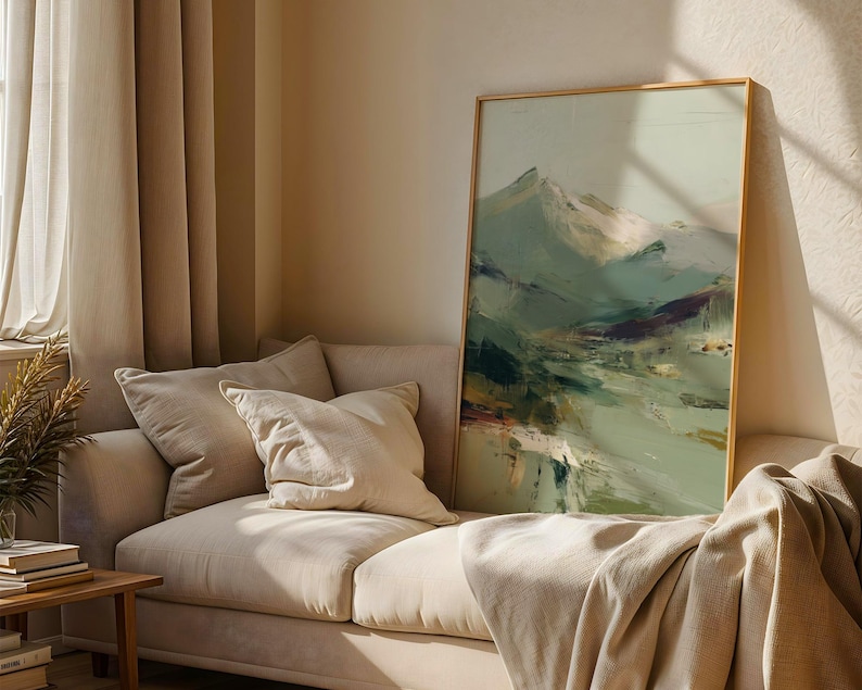 a cozy living room with a beige sofa, a large framed landscape painting on the wall, and a window with curtains.