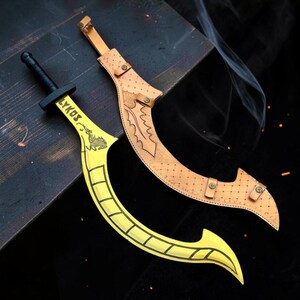 May include: A yellow curved sword with a black handle and the word LYKOS printed on the blade, accompanied by a tan leather sheath featuring decorative stitching, metal rivets, and a leaf-like pattern embossed along the curved edge of the scabbard.