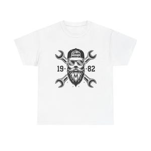 May include: White t-shirt featuring a black and white graphic of a bearded man wearing sunglasses and a cap, with crossed wrenches behind him. The numbers "19+82" are on either side of the man's head.