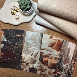 May include: A collection of lifestyle items on a wooden surface. Includes a white, wavy tray with gold earrings, a ring, and a small succulent. There are also cream-colored notebooks and four postcards with winter scenes.
