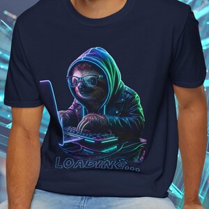 Könnte beinhalten: Marineblaues T-Shirt mit einem Faultier, das Brille und Kapuzenpullover trägt und an einem Laptop arbeitet. Die Grafik hat neon-grüne und blaue Akzente, darunter steht das Wort "LOADING...". Das Shirt hat einen Rundhalsausschnitt und kurze Ärmel.
