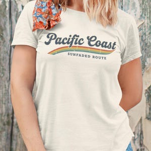 Puede incluir: Una taza de cerámica blanca con un asa negra y el texto "But First, Coffee" en negro, en negrita. La taza está sobre una superficie de madera.