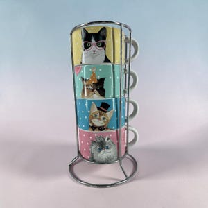 Juego de 4 tazas apilables con diseño de gato de Pier 1 Imports, estilo vintage, con soporte metálico y cerámica.