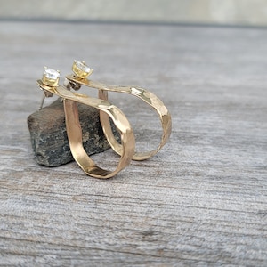 May include: A pair of gold hammered hoop earrings with a small clear gemstone accent.