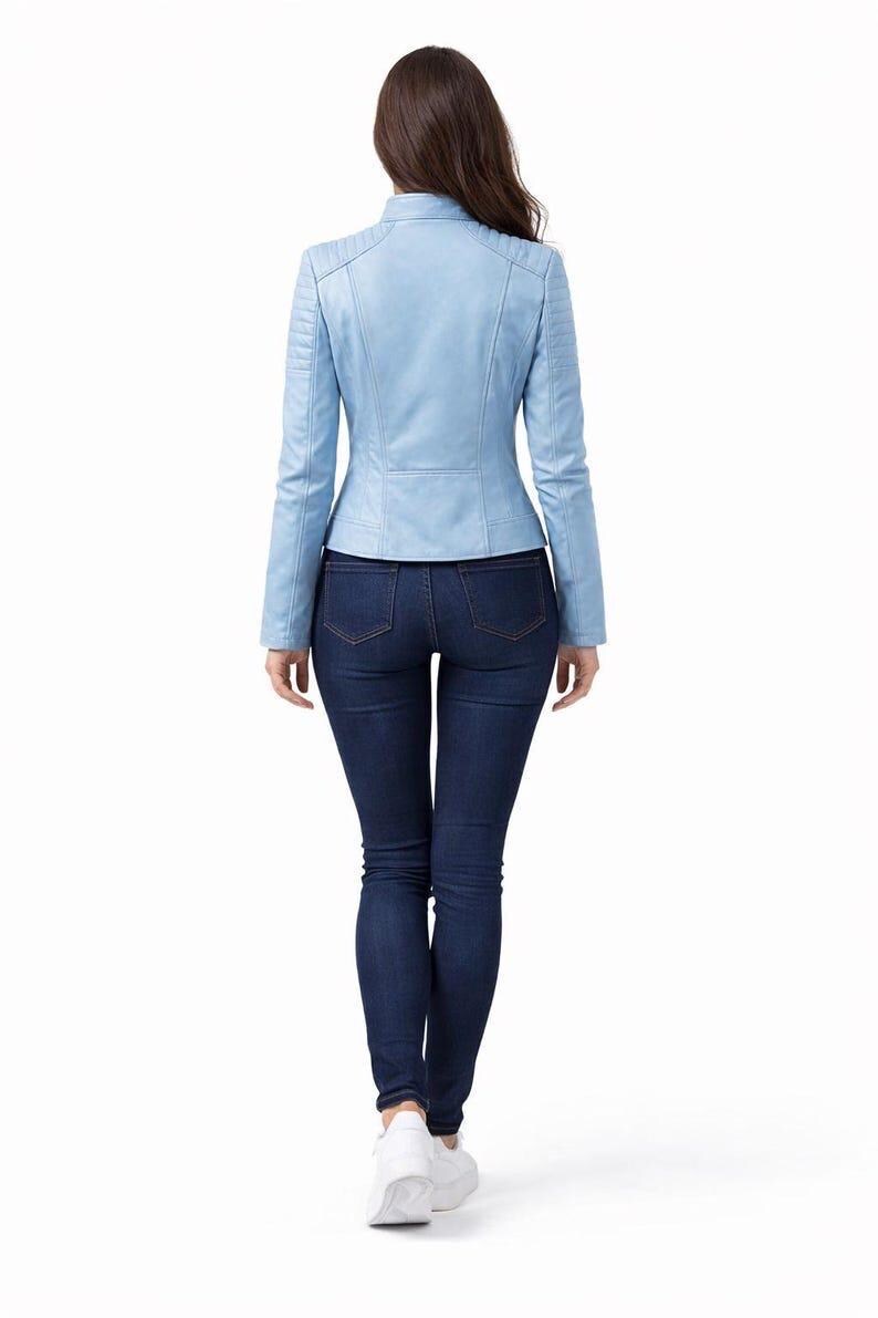 May include: A light blue leather jacket with a stand-up collar and long sleeves. The jacket is paired with dark blue skinny jeans and white sneakers. The model is viewed from the back.