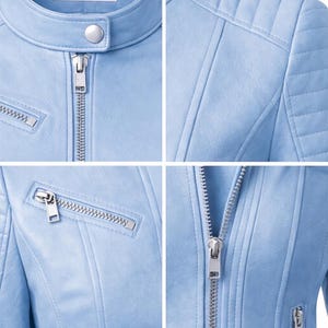May include: Close-up of a light blue jacket with a stand-up collar and silver zipper. The jacket has quilted shoulder details and a small pocket with a zipper. The brand name "Veloura" is visible on a tag.
