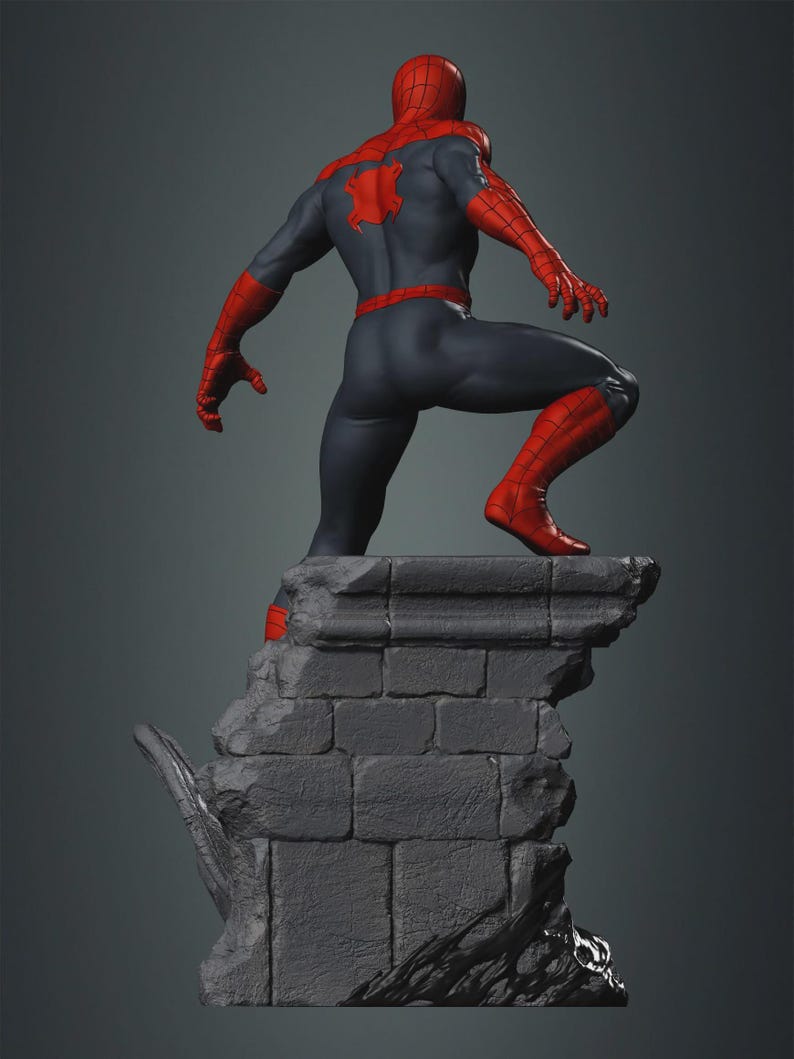 May include: A detailed statue of a superhero in a dynamic pose, viewed from the back. The figure wears a red and blue suit, with a spider emblem on the back. The statue is perched atop a gray, textured stone structure, with a dark gray background.
