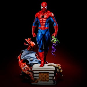 May include: A detailed figurine of Spider-Man in his classic red and blue suit, holding the Green Goblin's mask. The statue stands on a brick-like platform with other villainous elements, set against a dark background.