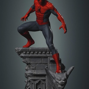 May include: A detailed statue of Spider-Man in a dynamic pose, wearing his classic red and blue suit. The figure is perched atop a gray, gothic-style stone structure with a gargoyle. The statue's pose suggests action and readiness.