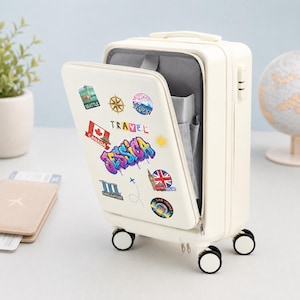 May include: A cream-colored hard-shell carry-on suitcase with a front-opening compartment. The exterior is decorated with various travel-themed stickers, including the name JESSICA in colorful graffiti-style lettering and the word TRAVEL.