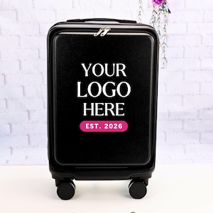 May include: A black hard-shell carry-on suitcase with four wheels and a top handle. The front features the white text "YOUR LOGO HERE" centered above a pink horizontal rectangle containing the white text "EST. 2026" in a clean, sans-serif font.