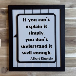 May include: A framed wall art piece with a black frame. The artwork features a white background with the quote "If you can't explain it simply, you don't understand it well enough. Albert Einstein" in black text.